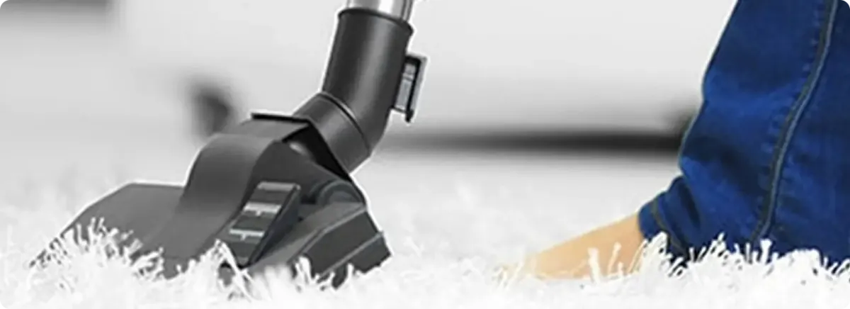 Close-up of a professional vacuuming a white carpet in Redondo.
