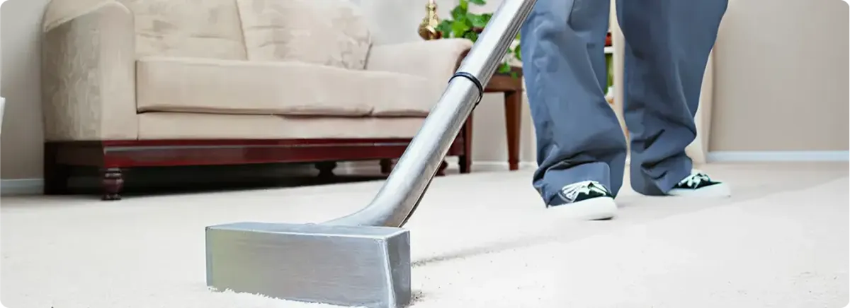 Carpet cleaning technician using a hot-water extraction wand on a light-colored carpet in a living room, Tacoma, WA.